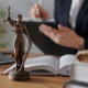 lady justice statue with someone signing papers