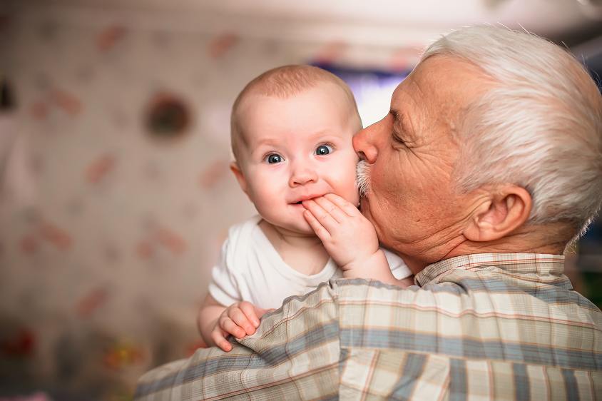 elderly man kissing baby on cheek